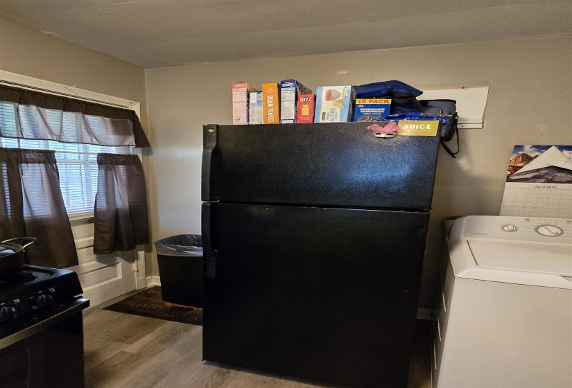 Kitchen featuring washer / clothes dryer, black appliances, and wood finished floors