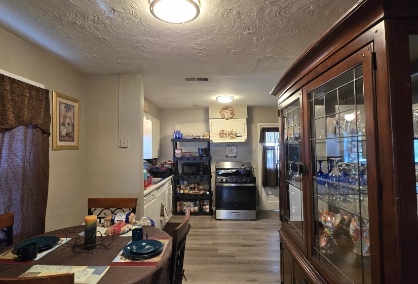 Kitchen featuring gas range, light wood finished floors, a textured ceiling, white cabinets, and black microwave