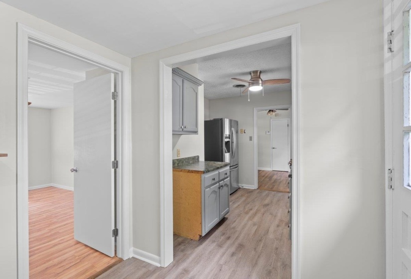 Kitchen with light wood-type flooring, stainless steel fridge, ceiling fan, a textured ceiling, and dark countertops