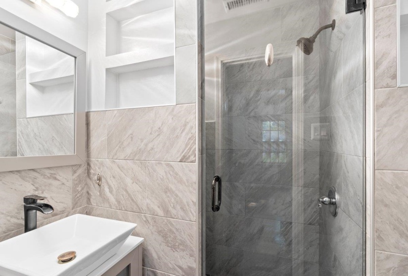 Full bath with a shower stall, vanity, and tile walls