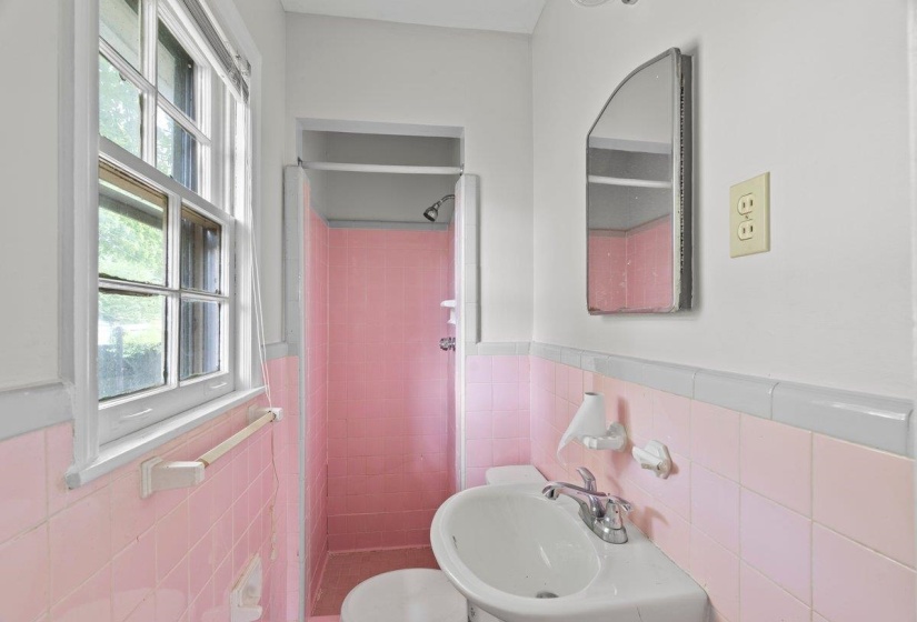 Bathroom with tile walls, a shower stall, and wainscoting