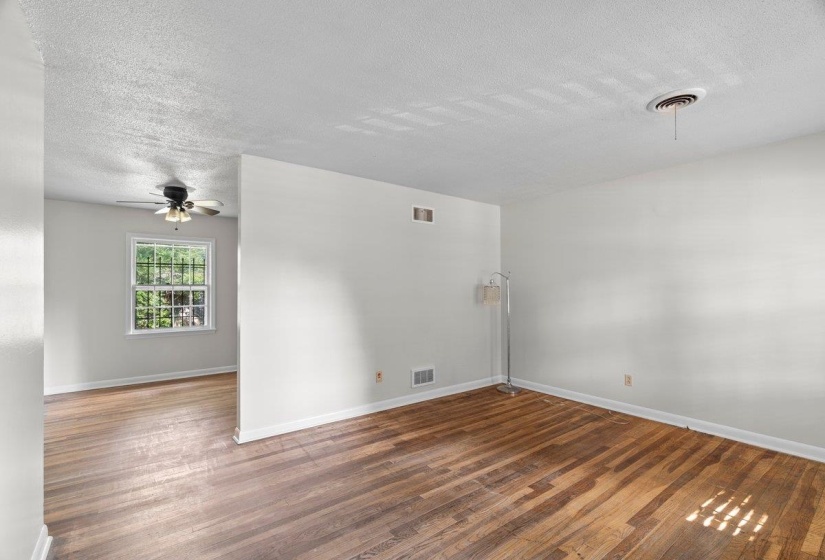 Unfurnished room featuring a textured ceiling, wood finished floors, and ceiling fan