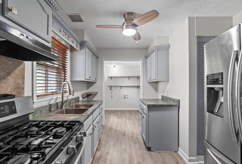 Kitchen with gray cabinets, stainless steel appliances, dark countertops, a textured ceiling, and light wood-style floors