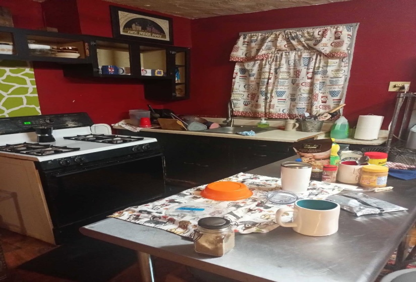 Kitchen with range with gas cooktop, dark cabinets, and open shelves