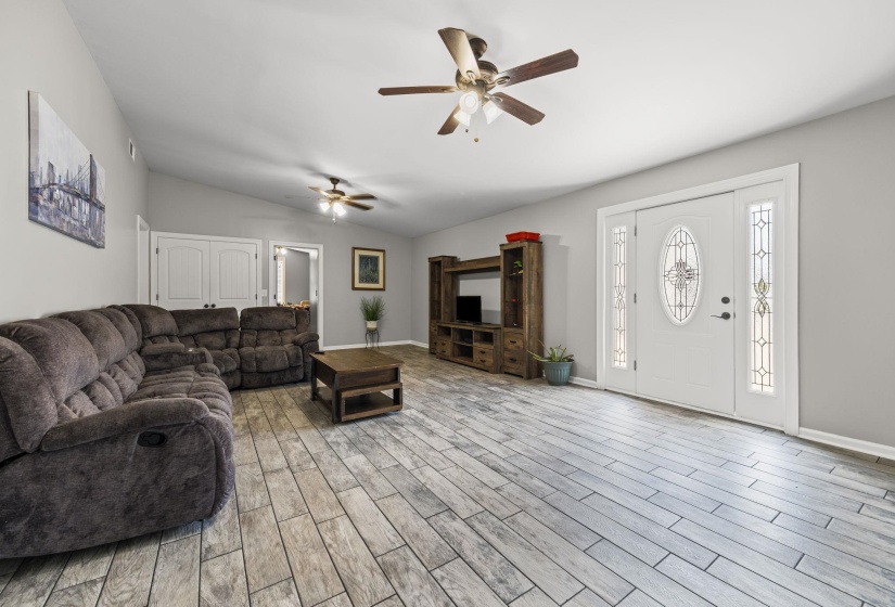 Living room with a ceiling fan, light wood-type flooring, and lofted ceiling