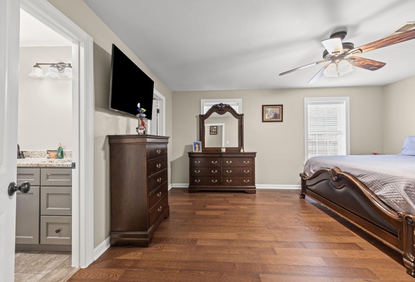 Bedroom with ensuite bath, ceiling fan, and dark wood-type flooring