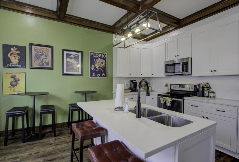 Kitchen with white cabinets, appliances with stainless steel finishes, dark wood finished floors, pendant lighting, and a breakfast bar area