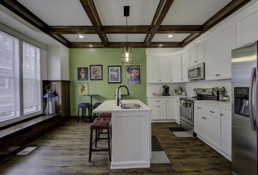 Kitchen with stainless steel appliances, decorative light fixtures, white cabinetry, a breakfast bar area, and dark wood finished floors