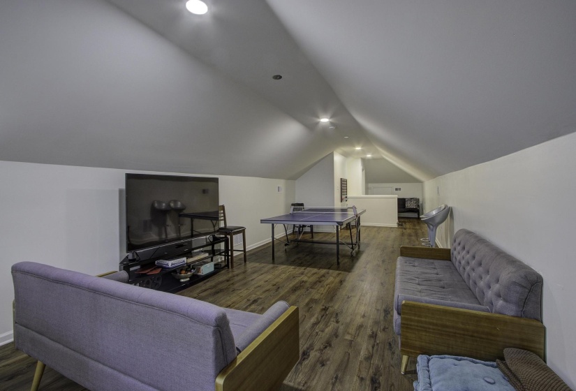 Living room with dark wood-style flooring, lofted ceiling, and recessed lighting