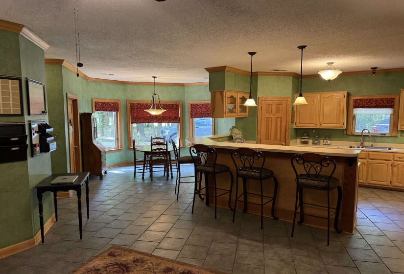Kitchen featuring ornamental molding, light countertops, a kitchen bar, plenty of natural light, and a textured ceiling