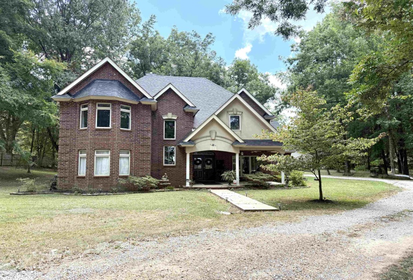 View of front of home with brick siding, a front yard, and covered porch