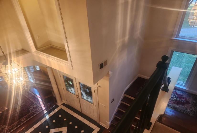 Tiled foyer entrance with inlaid floor details, a high ceiling, and healthy amount of natural light