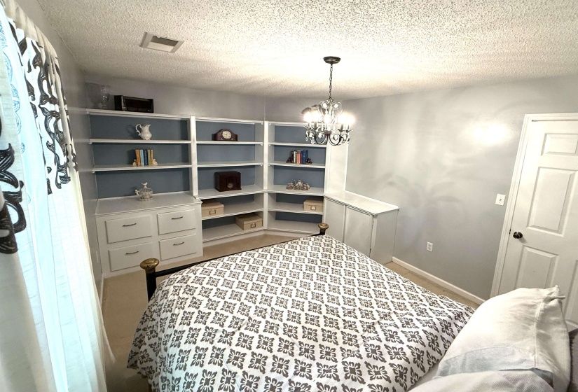 Bedroom with a textured ceiling, a chandelier, and carpet