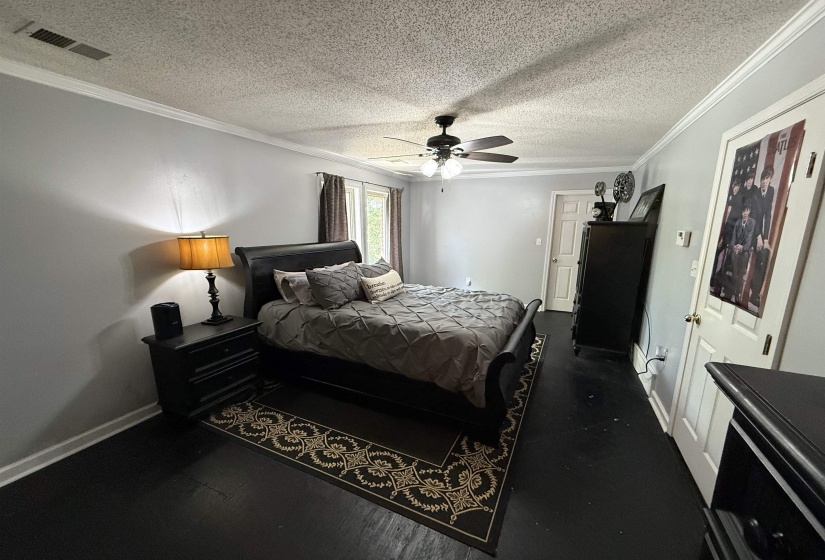 Bedroom with ornamental molding, a textured ceiling, and a ceiling fan