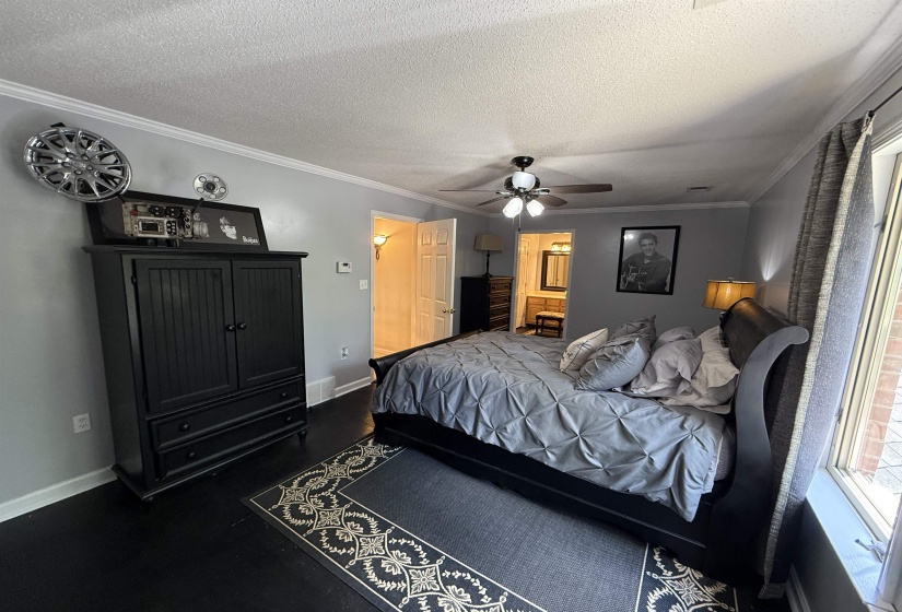 Bedroom featuring crown molding, a textured ceiling, ensuite bathroom, ceiling fan, and dark wood finished floors