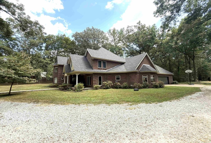 View of front of property with a porch, a front yard, a garage, and driveway