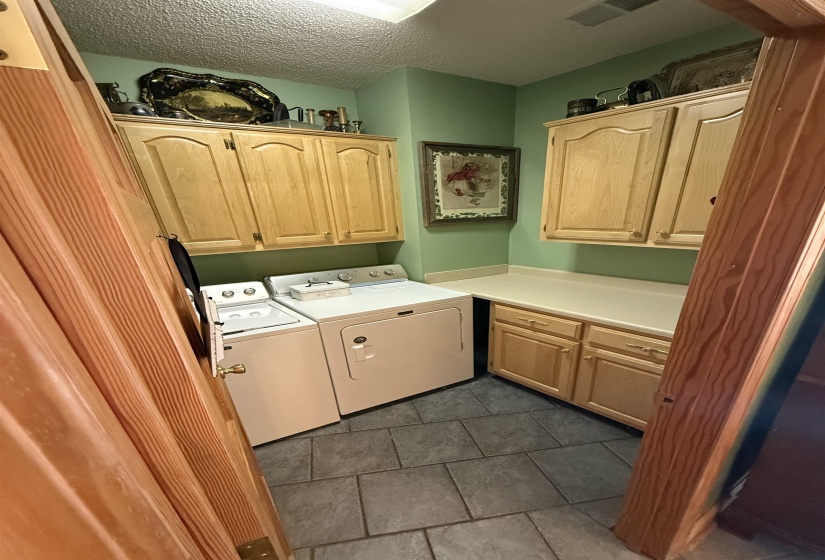 Laundry area featuring cabinet space, a textured ceiling, washing machine and dryer, and dark tile patterned flooring