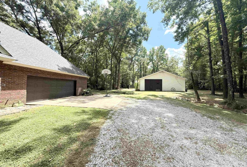 View of green lawn with a detached garage and an outbuilding