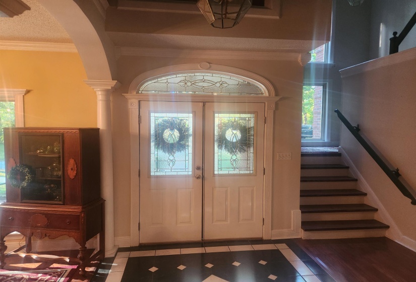 Tiled foyer entrance with ornamental molding, french doors, plenty of natural light, and stairway