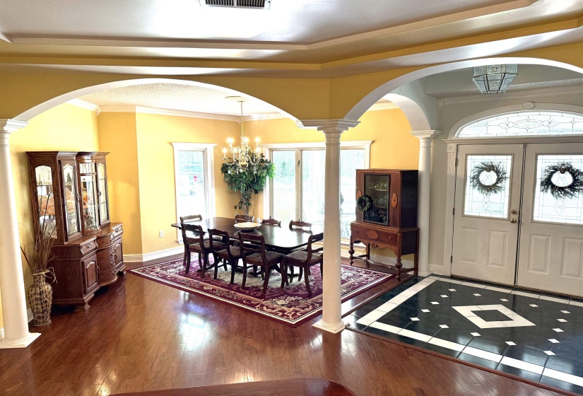 Entrance foyer with arched walkways, decorative columns, a chandelier, plenty of natural light, and crown molding