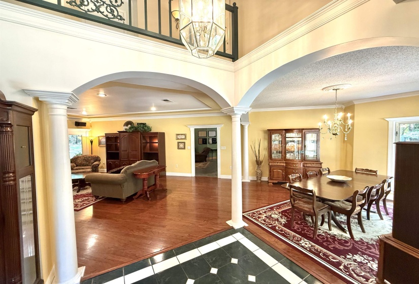 Dining space featuring a chandelier, ornate columns, dark tile patterned flooring, plenty of natural light, and ornamental molding