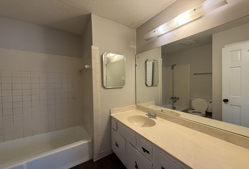 Full bath with tub / shower combination, a textured ceiling, and vanity