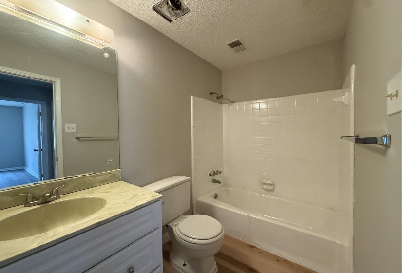 Bathroom featuring  shower combination, a textured ceiling, vanity, and wood finished floors