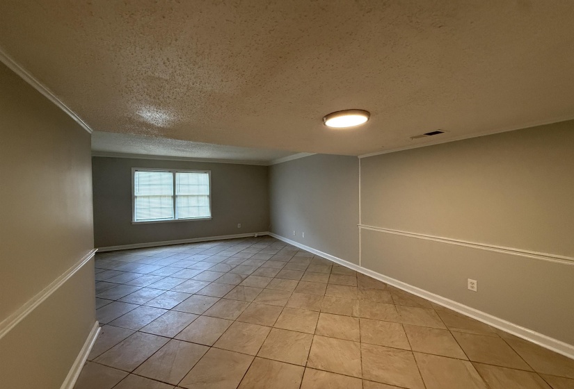 Unfurnished room featuring a textured ceiling, light tile patterned floors, and ornamental molding