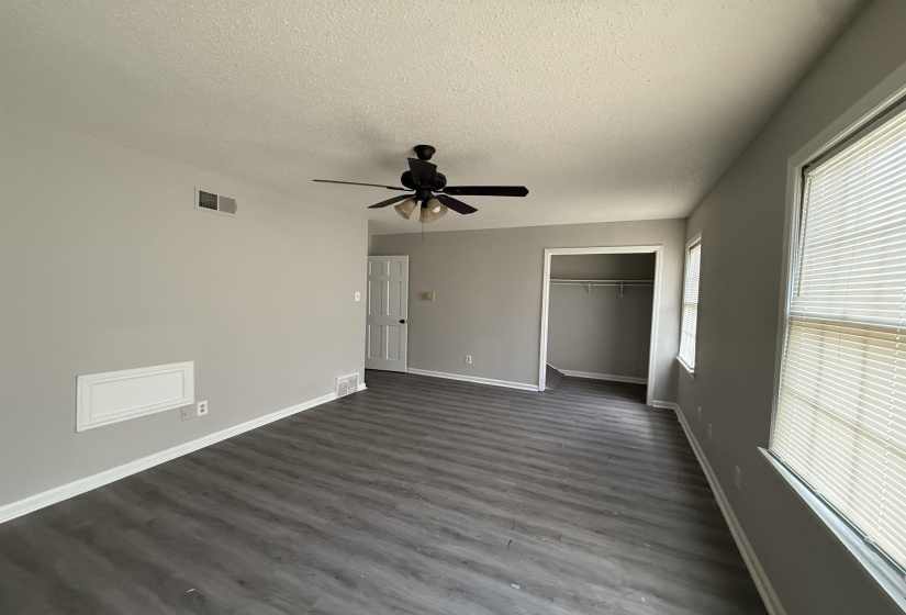 Unfurnished bedroom featuring a textured ceiling, dark wood finished floors, a closet, and ceiling fan
