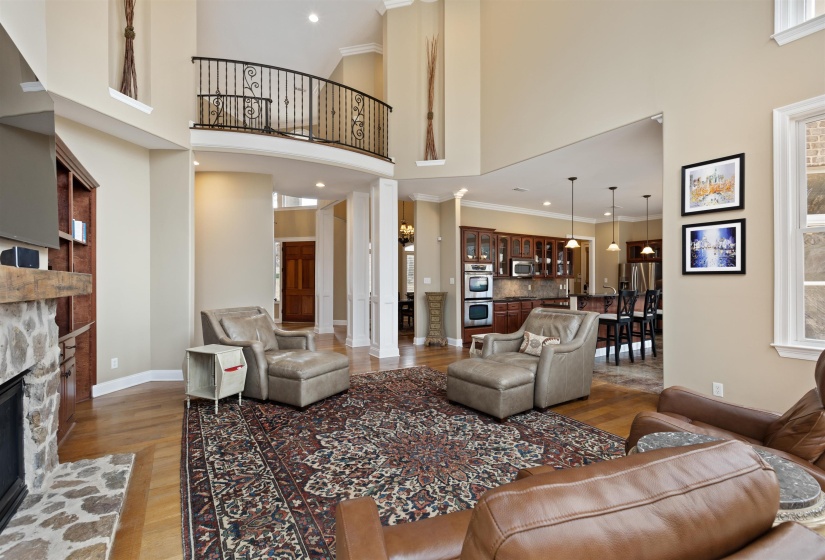 Living room with wood-type flooring, ornate columns, a fireplace, and a high ceiling