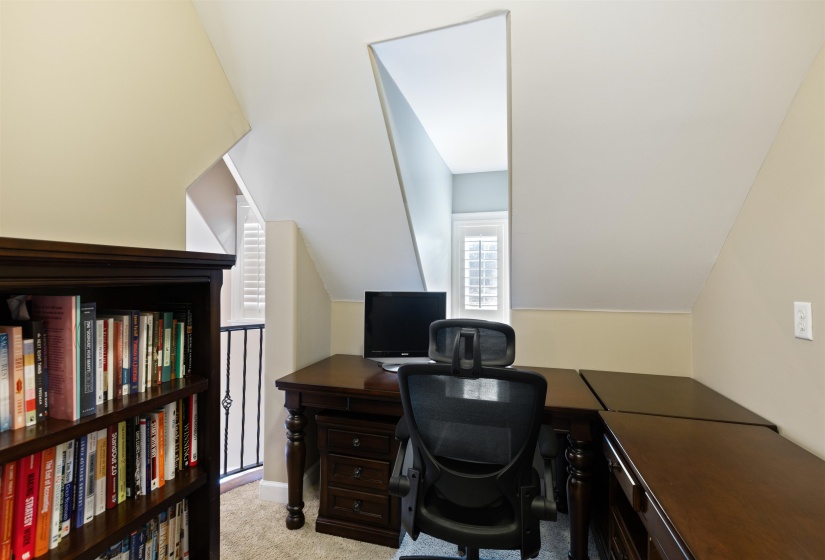 Carpeted home office with lofted ceiling