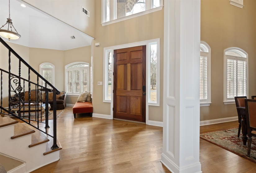 Entrance foyer with hardwood / wood-style flooring, a towering ceiling, and ornate columns