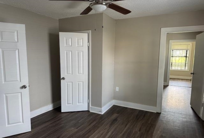 Unfurnished bedroom featuring dark wood-type flooring, baseboards, and a textured ceiling