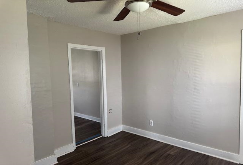 Spare room featuring ceiling fan, a textured ceiling, baseboards, and dark wood-style floors