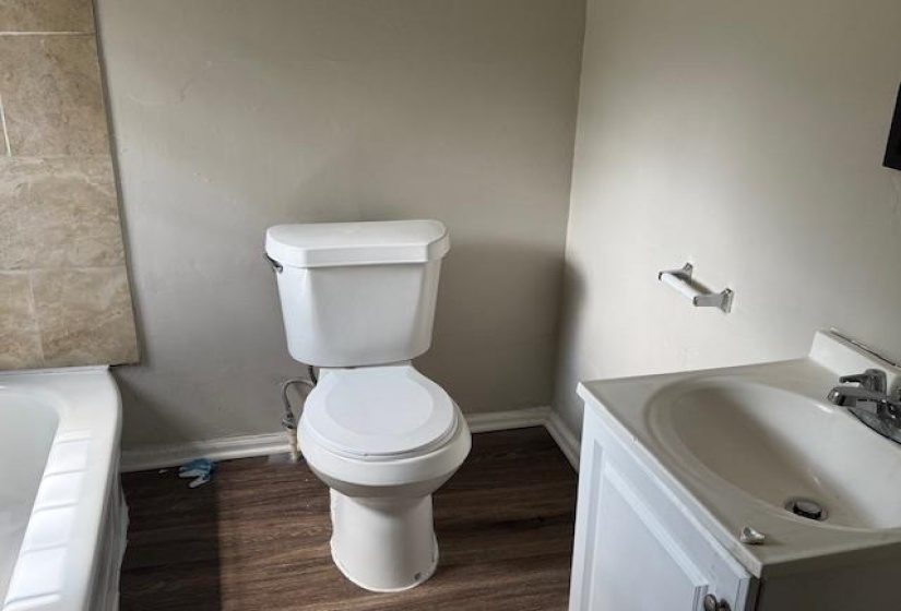 Full bath with vanity, a bath, toilet, and wood finished floors