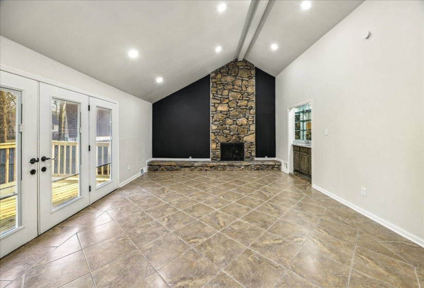 Unfurnished den featuring high vaulted ceiling, a fireplace, and beam ceiling