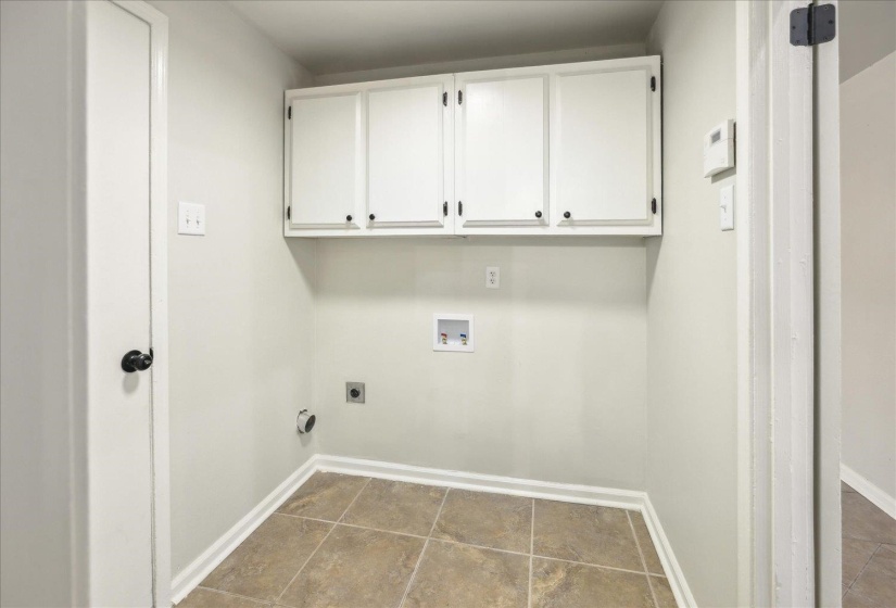 Clothes washing area with electric dryer hookup, hookup for a washing machine, and cabinets
