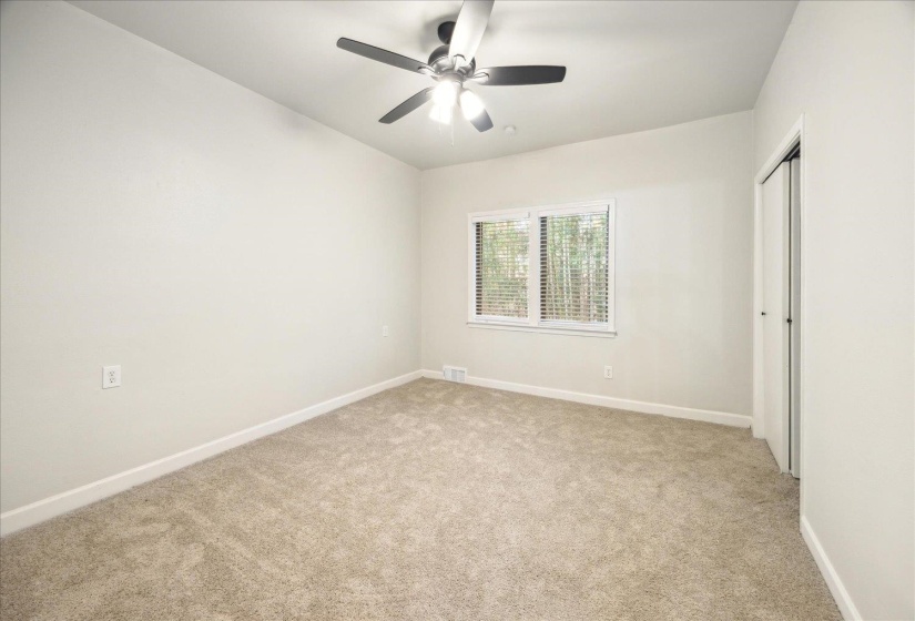 Unfurnished bedroom featuring ceiling fan, light colored carpet, and a closet