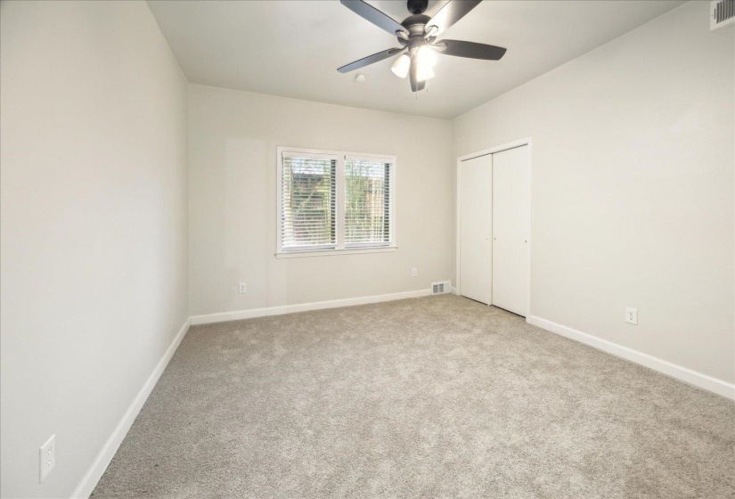 Unfurnished bedroom featuring ceiling fan, light colored carpet, and a closet