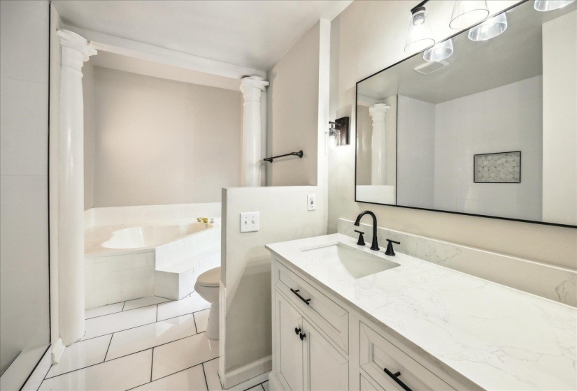 Bathroom with vanity, tile patterned floors, tiled bath, and toilet