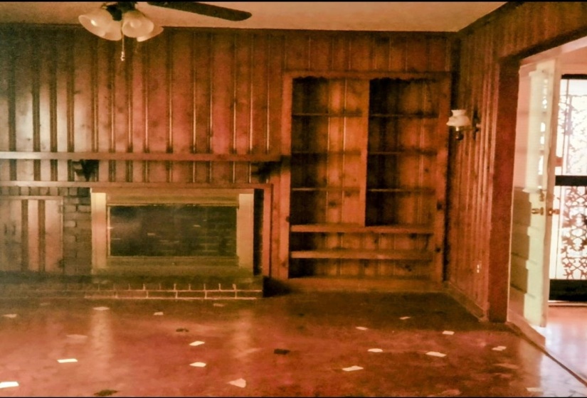 Unfurnished living room with a ceiling fan and wood walls
