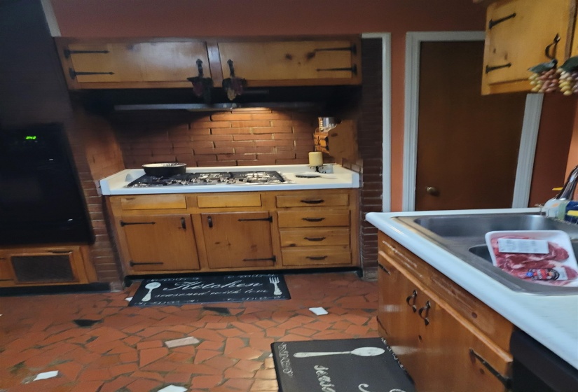 Kitchen featuring light countertops, wood finish cabinets, stainless steel gas stovetop, and decorative backsplash