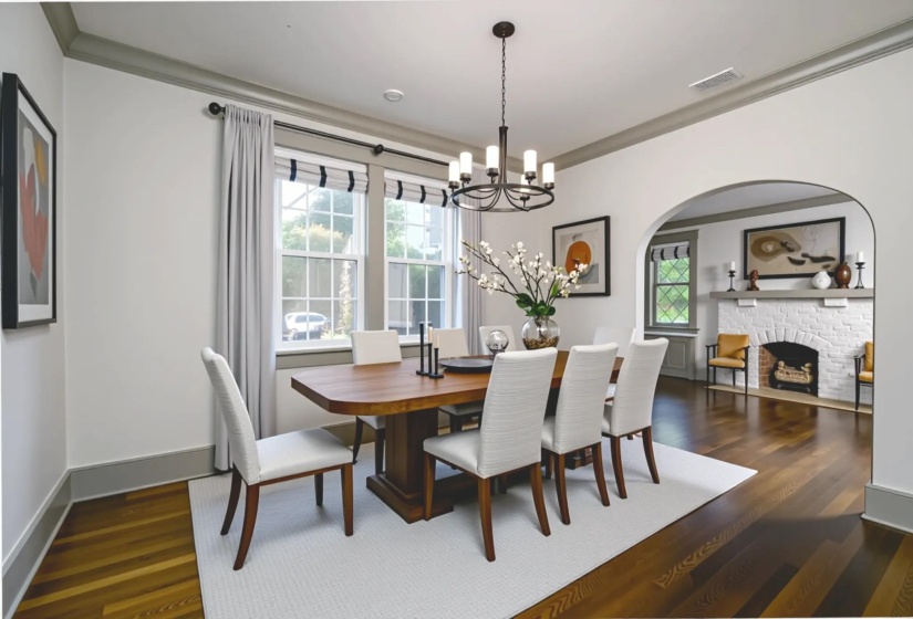 Dining space featuring plenty of natural light, crown molding, dark wood finished floors, a chandelier, and a fireplace