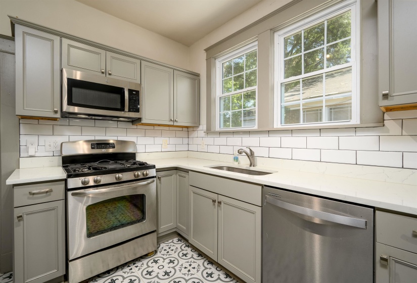 Kitchen featuring gray cabinets, appliances with stainless steel finishes, light stone countertops, and backsplash