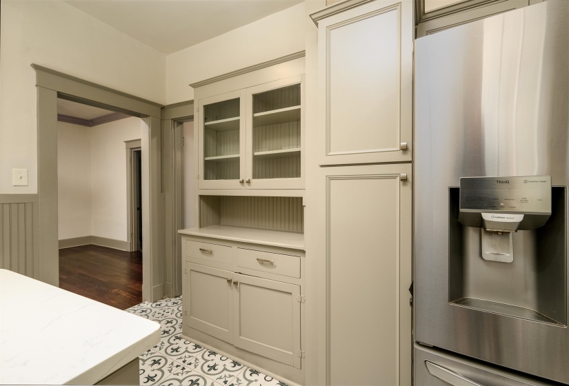 Kitchen with stainless steel refrigerator with ice dispenser, glass insert cabinets, and light tile patterned flooring