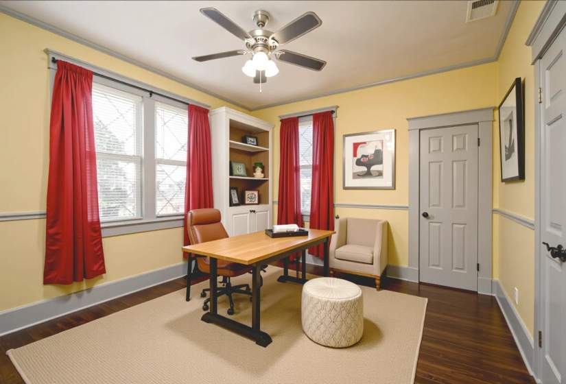 Office area featuring dark wood-style flooring, ornamental molding, and ceiling fan