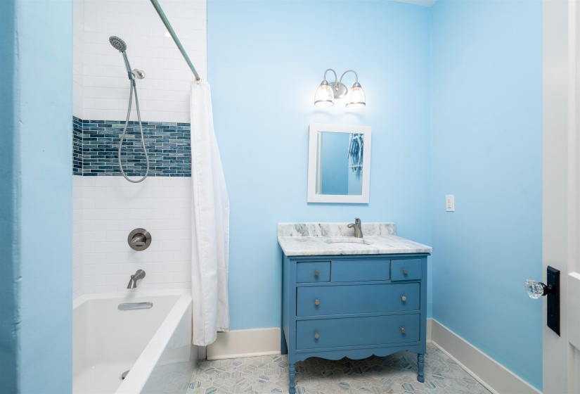 Full bath featuring shower / bath combo, vanity, and light tile patterned floors