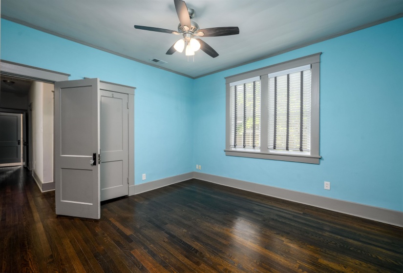 Unfurnished bedroom featuring dark wood-style flooring, crown molding, ceiling fan, and a closet