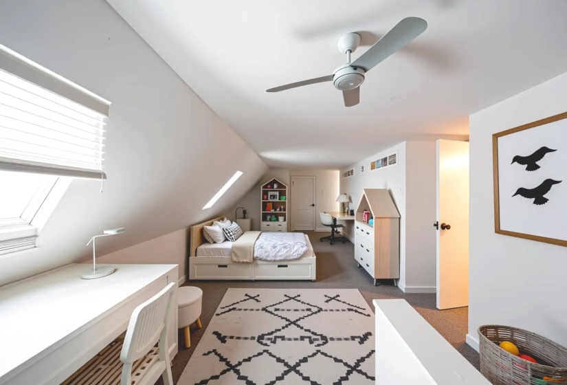 Carpeted bedroom with a skylight, lofted ceiling, and a ceiling fan