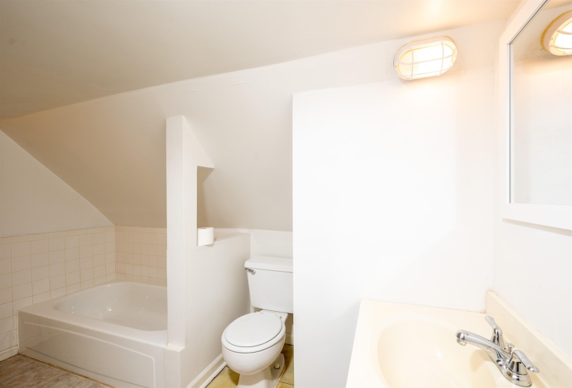 Bathroom featuring a bath, vaulted ceiling, tile patterned flooring, and vanity